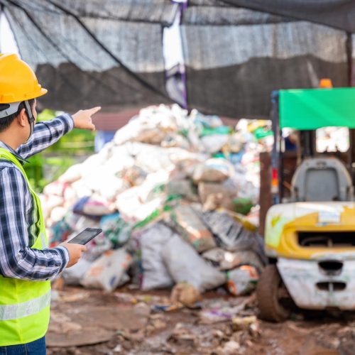 asian-foreman-working-recycling-factory-holding-tablet-looking-recycle-waste-factory-with-forklift-background-min